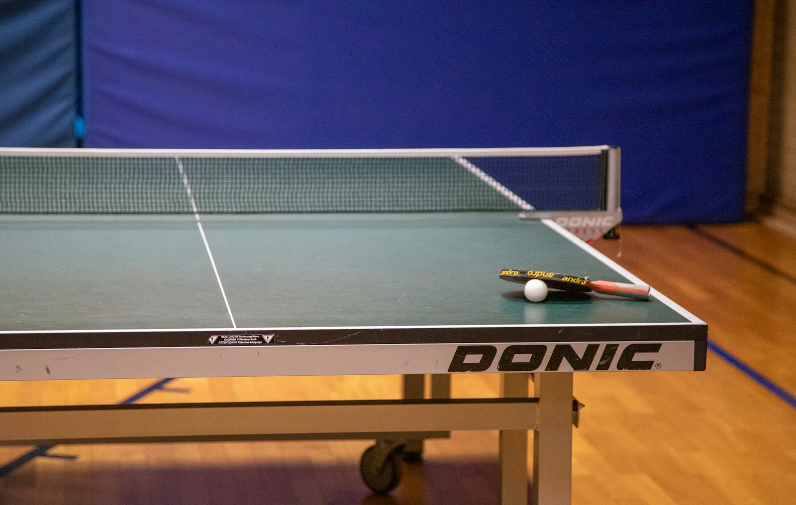 A table tennis table with a paddle and ball in a community gym